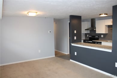 Kitchen featuring wall chimney range hood, black e