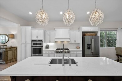 Kitchen featuring stainless steel appliances, a chandelier, a large island, wall chimney range hood, and recessed lighting