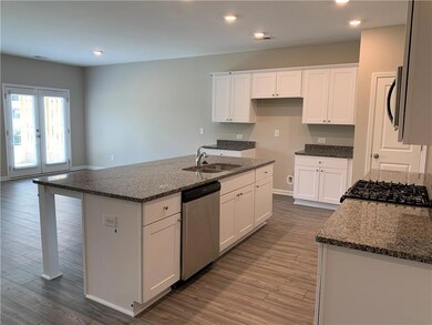 Kitchen with stainless steel appliances, white cabinets, dark wood-style floors, dark stone countertops, and recessed lighting