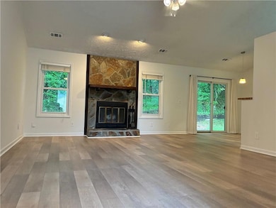 Unfurnished living room featuring wood finished floors, ceiling fan, baseboards, and a fireplace