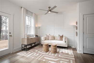 Living area featuring a ceiling fan, a decorative wall, and wood finished floors