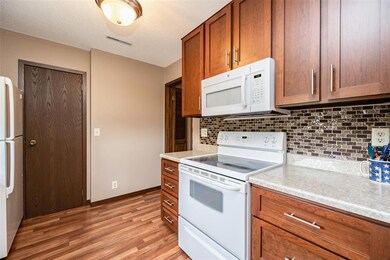 Kitchen has engineered floors, white appliances, b