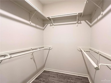 Walk in closet with dark wood-type flooring