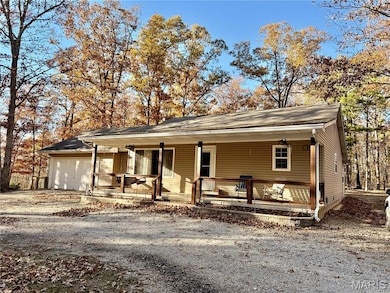 View of front of property featuring covered porch, driveway, and a garage