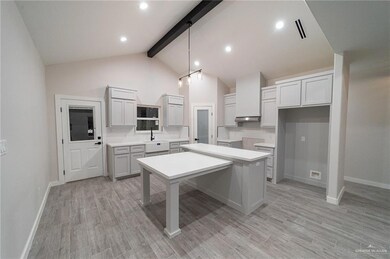 Kitchen featuring decorative backsplash, light countertops, beam ceiling, a kitchen island, and a kitchen bar