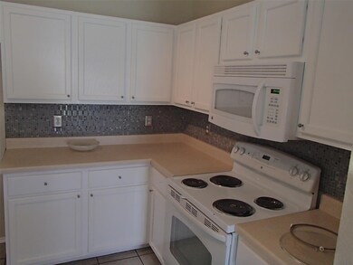Kitchen with white appliances, white cabinetry, l