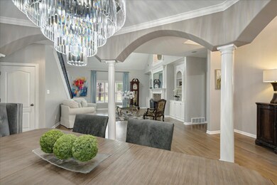 Dining space with hardwood / wood-style floors, crown molding, and decorative columns