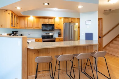 Kitchen featuring stainless steel appliances, a peninsula, glass insert cabinets, light wood-style floors, and light countertops