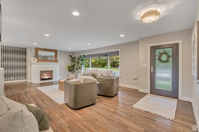 Living room featuring light wood-type flooring, recessed lighting, and a fireplace with flush hearth