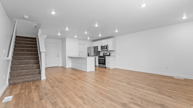 Unfurnished living room with stairs, light wood-type flooring, and recessed lighting