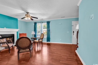 Dining space featuring a textured ceiling, a ceiling fan, wood finished floors, baseboards, and crown molding