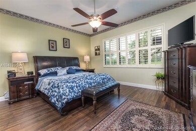 Huge master bedroom has wood flooring. Ceiling fan
