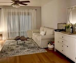 Living area featuring ceiling fan and dark wood f