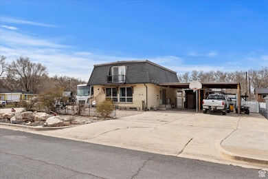 View of front of house with roof with shingles, a balcony, driveway, mansard roof, and an attached carport