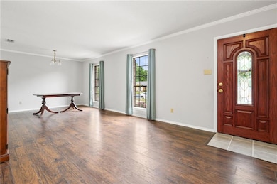 Foyer entrance featuring wood-type flooring, crown molding, baseboards, and a chandelier