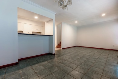 Unfurnished living room featuring a chandelier, dark tile patterned flooring, and ornamental molding
