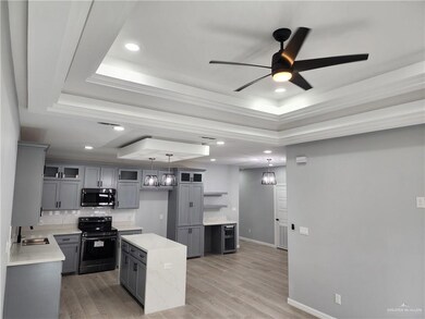 Kitchen with range with electric cooktop, ceiling fan with notable chandelier, light wood-type flooring, and a kitchen island