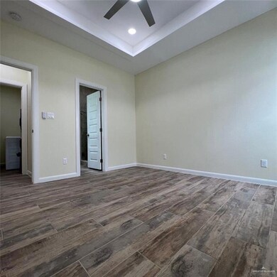 Unfurnished bedroom featuring dark wood-type flooring, a tray ceiling, ceiling fan, and recessed lighting