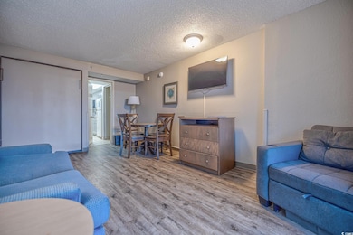 Living room with a textured ceiling, wood finished floors, and baseboards