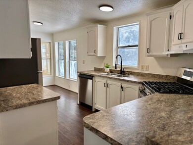 Kitchen featuring dark countertops, appliances with stainless steel finishes, white cabinetry, a textured ceiling, and crown molding