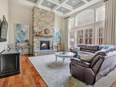 Family room with towering coffer ceiling, stone gas fireplace, wall of windows overlooking the private rear yard. Beautiful hardwood floors!
