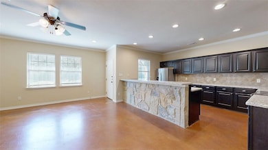 Kitchen with tasteful backsplash, ornamental molding, stainless steel fridge, finished concrete flooring, and recessed lighting