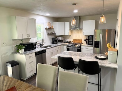 Kitchen featuring wall chimney exhaust hood, appli
