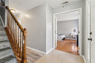 Stairway with tile patterned floors and a textured ceiling