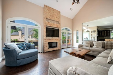 Living area with french doors, high vaulted ceiling, plenty of natural light, dark wood-style flooring, and a fireplace