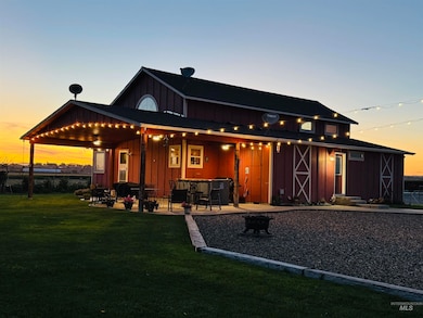 Back of house at dusk with board and batten siding, a lawn, a patio area, and an outdoor fire pit