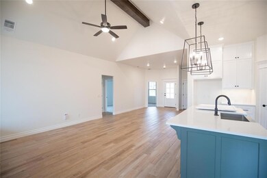 Kitchen with beam ceiling, open floor plan, high vaulted ceiling, a ceiling fan, and light countertops