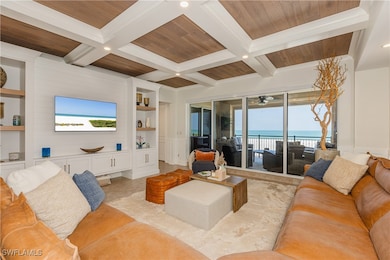 Tiled living room with beam ceiling, built in features, a beach view, and coffered ceiling