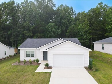 Ranch-style home featuring concrete driveway, a garage, and a front lawn