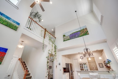 Staircase featuring a high ceiling, a chandelier, and ceiling fan