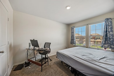 Carpeted bedroom with baseboards and a desk