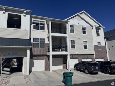 Back of property featuring driveway, a garage, a standing seam roof, a metal roof, and brick siding