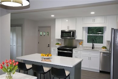 Kitchen featuring appliances with stainless steel finishes, a breakfast bar area, decorative backsplash, recessed lighting, and light countertops