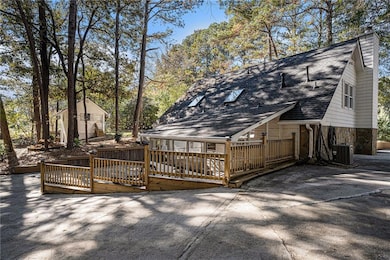 Rear view of house featuring roof with shingles, a wooden deck, a chimney, and view of scattered trees