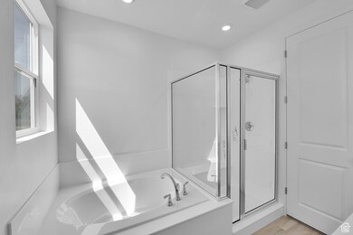 Bathroom featuring a shower stall, a bath, recessed lighting, and wood finished floors