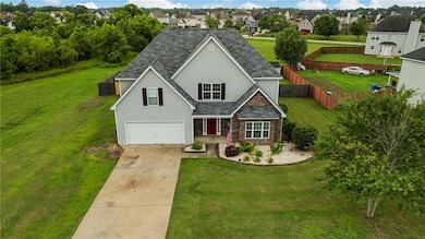 Traditional-style home featuring driveway, stone siding, an attached garage, a residential view, and a shingled roof