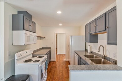 Kitchen with white appliances, a sink, dark wood-s