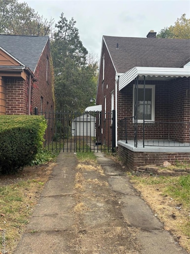 View of property exterior featuring brick siding, a gate, roof with shingles, and a chimney