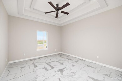 Unfurnished room featuring a tray ceiling, light tile floors, and ceiling fan