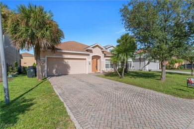 View of front facade with a front yard, stucco siding, decorative driveway, and an attached garage