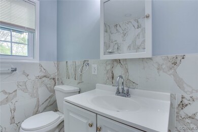 Bathroom featuring tile walls, wainscoting, vanity