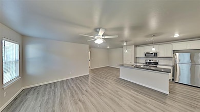Kitchen with appliances with stainless steel finishes, dark countertops, light wood-style floors, and ceiling fan