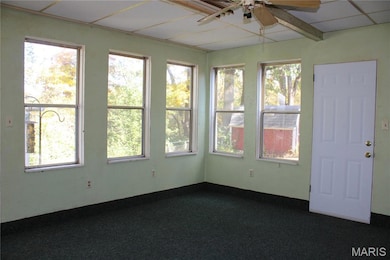 Unfurnished sunroom with a drop ceiling and carpet floors