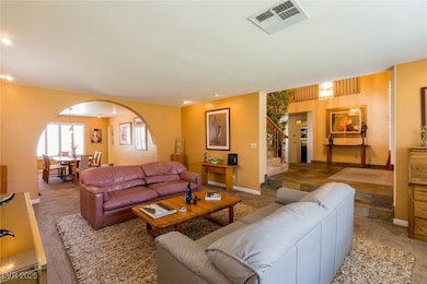 Living area with arched walkways, stairway, and ca