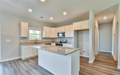 Kitchen featuring appliances with stainless steel finishes, a sink, white cabinets, and recessed lighting