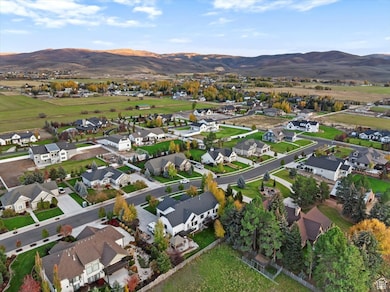 Aerial view of property and surrounding area featuring a mountainous background and nearby suburban area